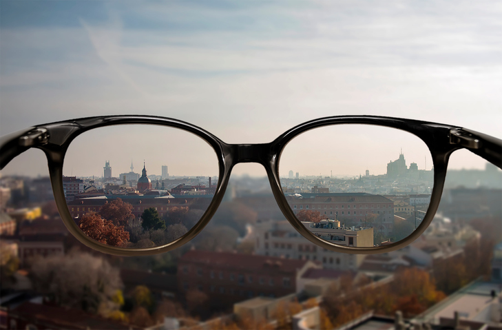 Myopia - blurred vision in the distance - blurred city backdrop and glasses with sharp vision