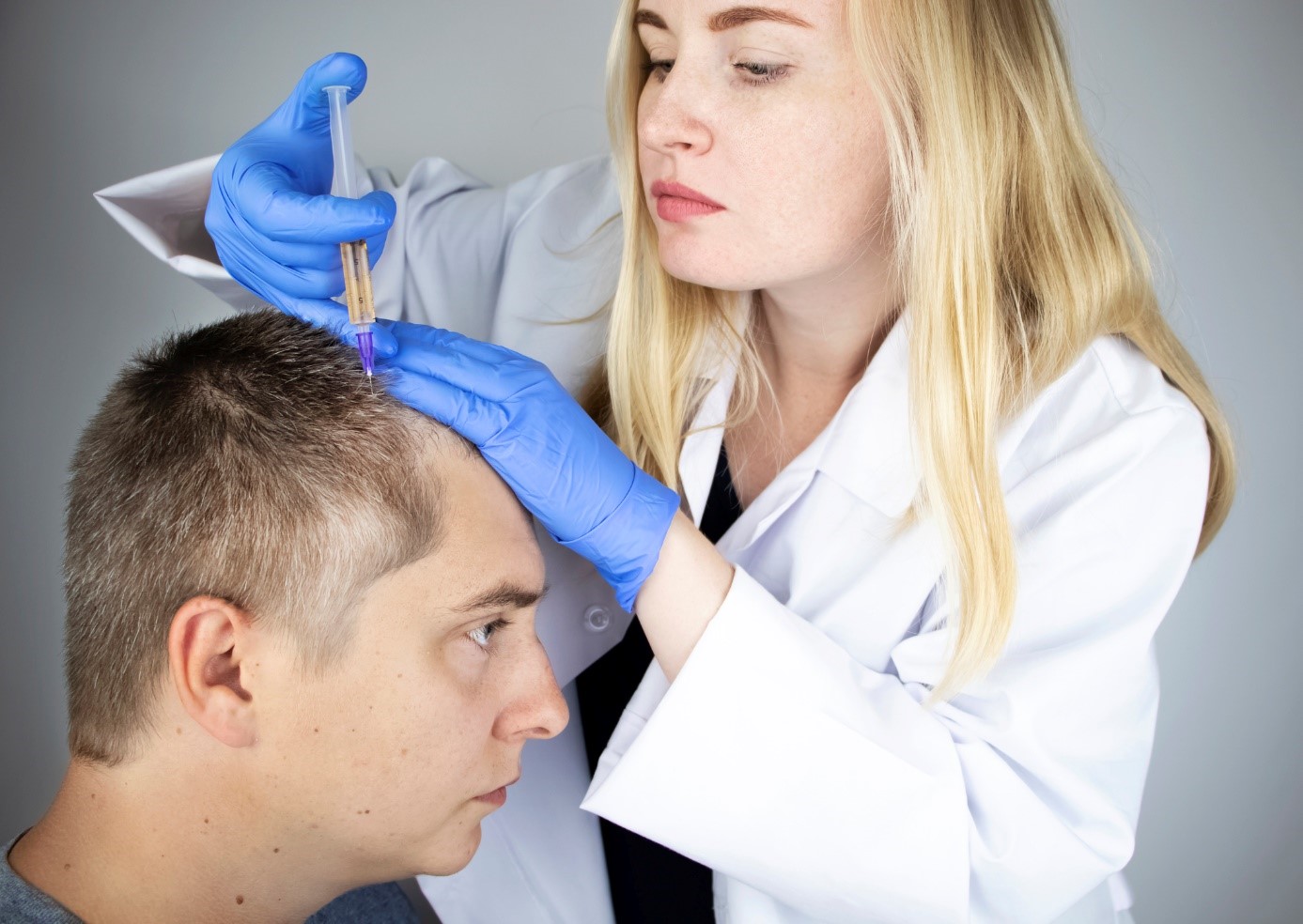 Treatment of hair loss, a doctor injects a drug into the head of a gentleman, a patient