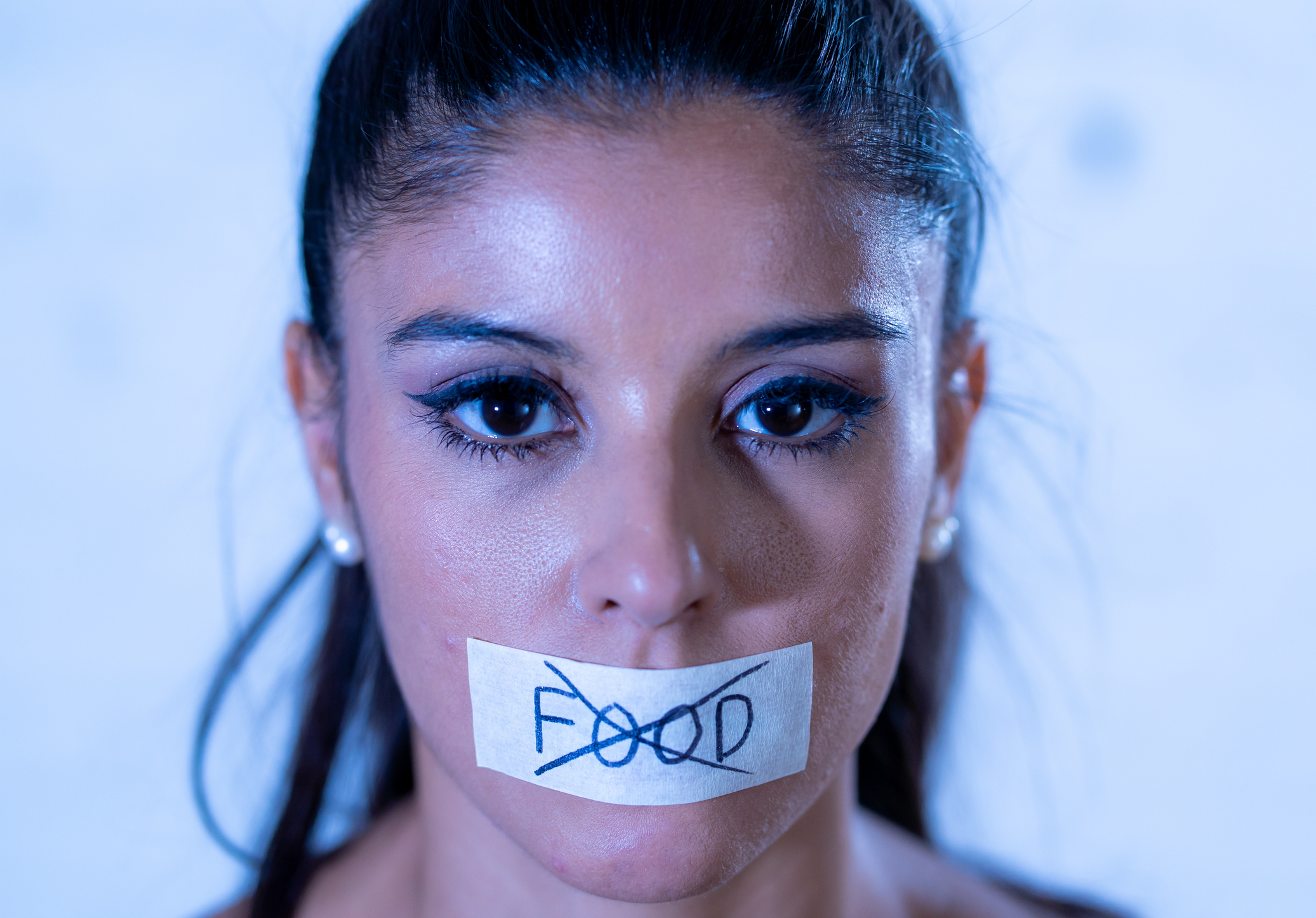 A woman with a tape over her mouth with the word food crossed out