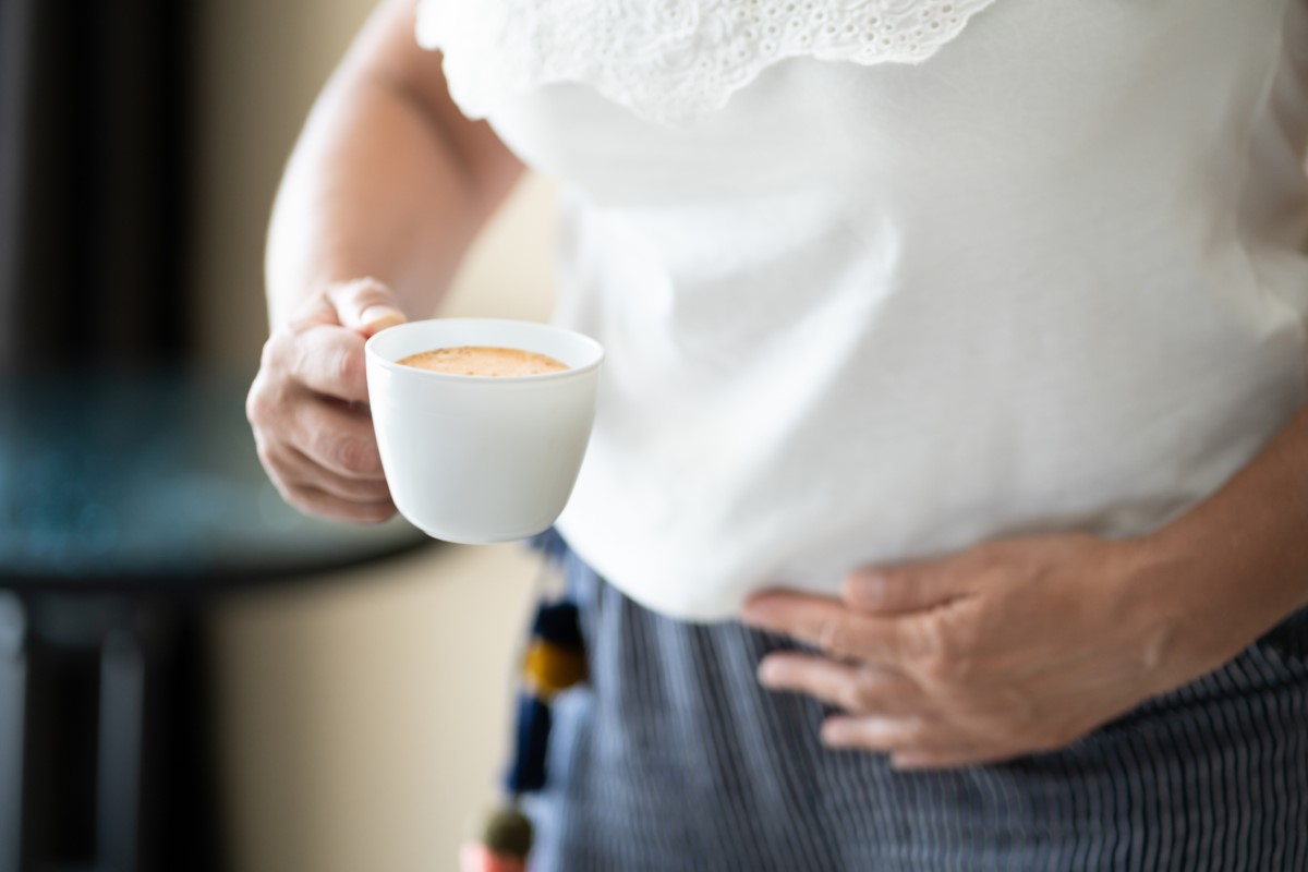 A cup of coffee in a person's hand as a risk factor for worsening reflux symptoms
