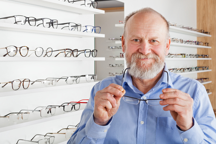 An elderly gentleman is holding a pair of glasses
