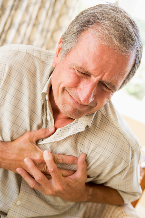 An elderly man holds his chest in the area of ​​the heart, has palpitations, ie palpitations and angina, ie chest pain