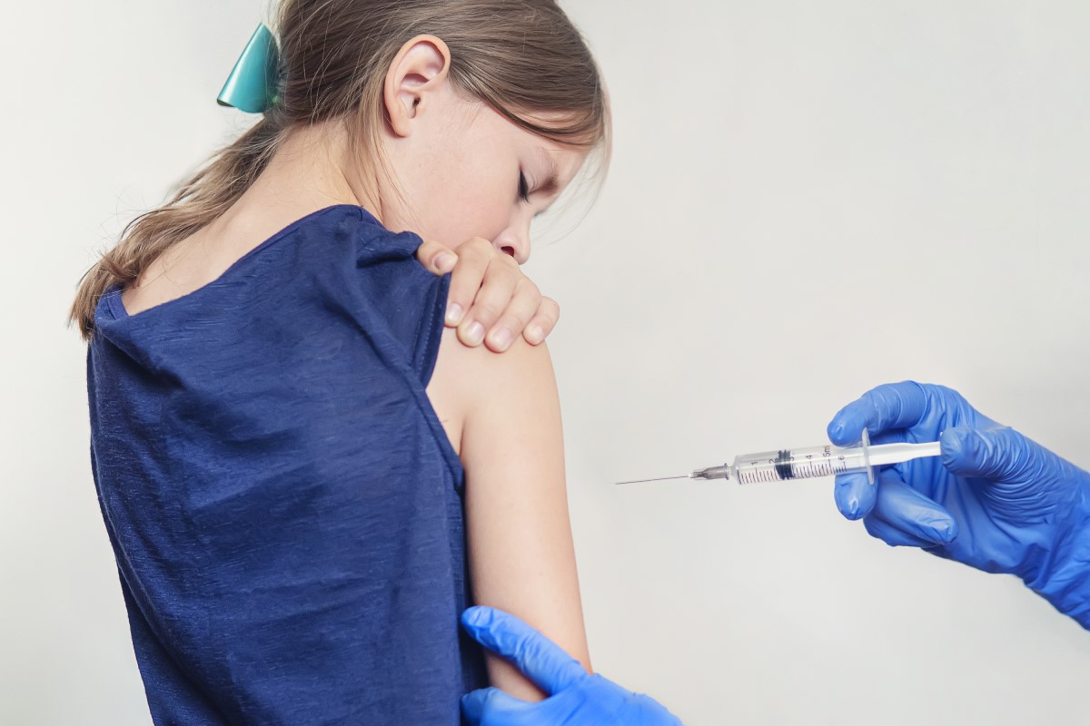 Vaccination of a child - a girl - the doctor injects a vaccine into the shoulder.