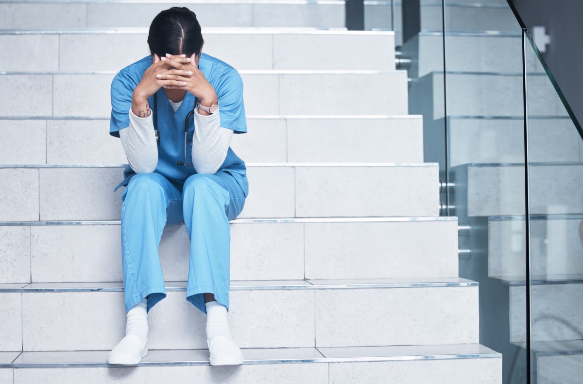 A nurse sits exhausted on the stairs and suffers from burnout syndrome