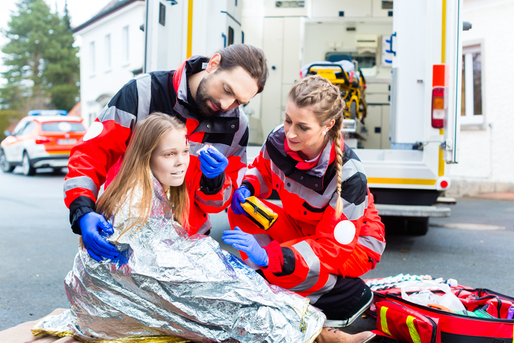 A girl with an injury is covered with a space blanket (a shock blanket) - it prevents heat loss