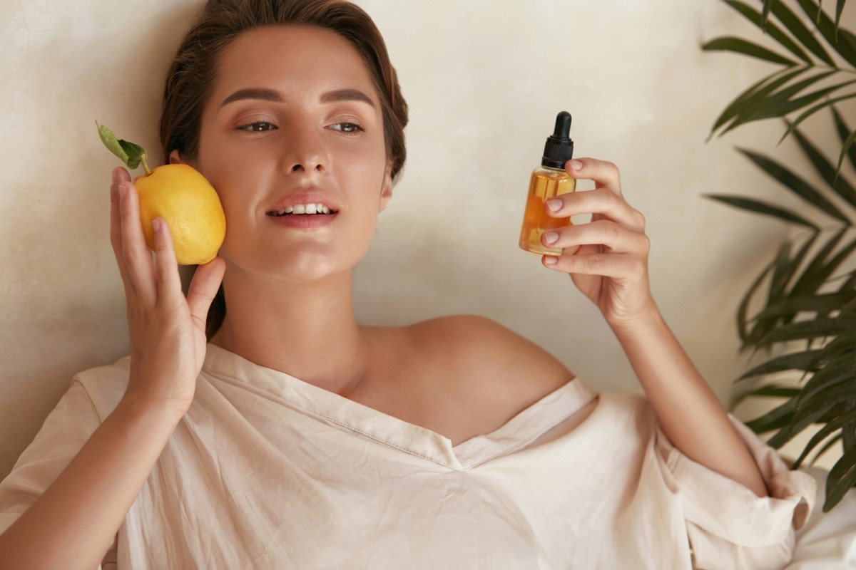 Woman with a lemon and a bottle of vitamin C extract in her hand, a vitamin that helps the skin
