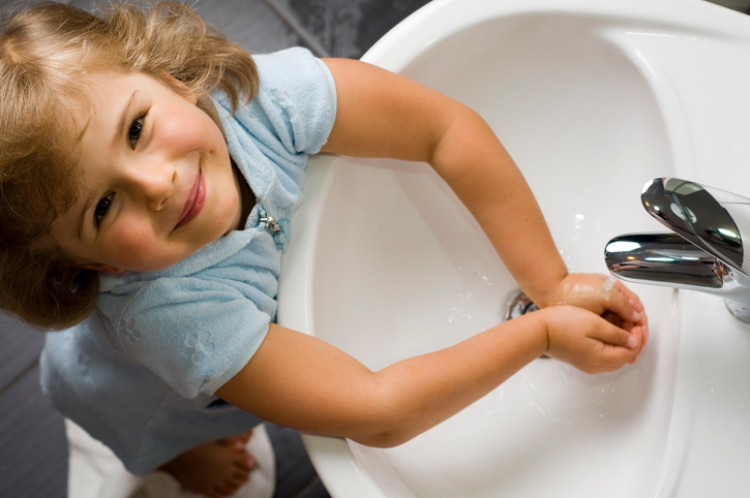 little girl washes her hands with clean water from the sink