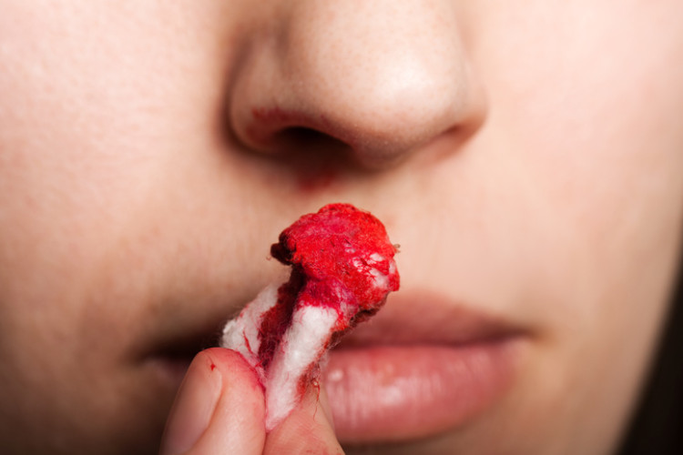 a woman holding a bloody tampon to her nose