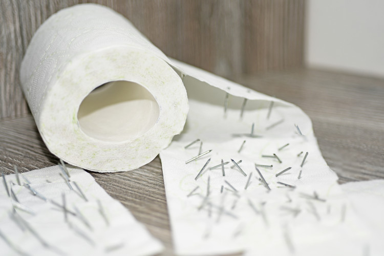 partially crumpled toilet paper pierced with small nails