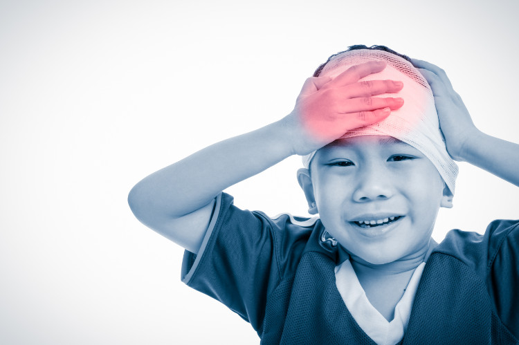 a child holds his head after an accident with a bandage