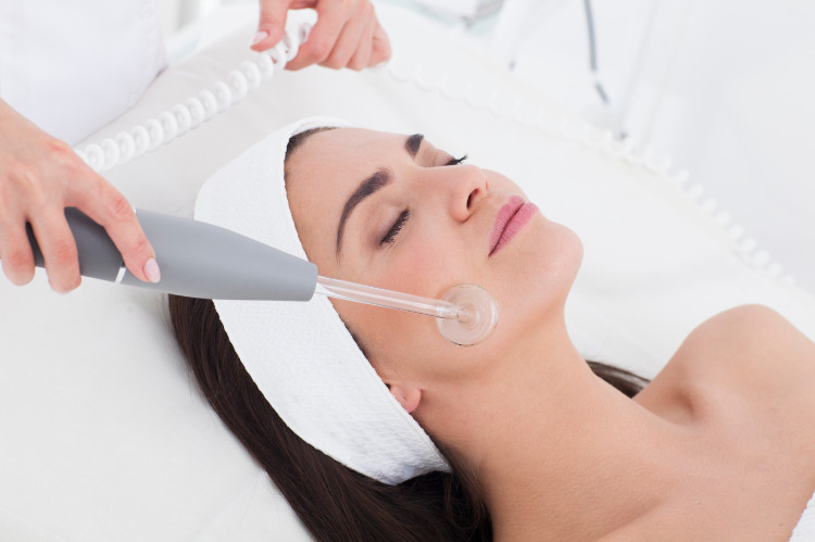 a woman in a white headband is having her face cleaned with a machine