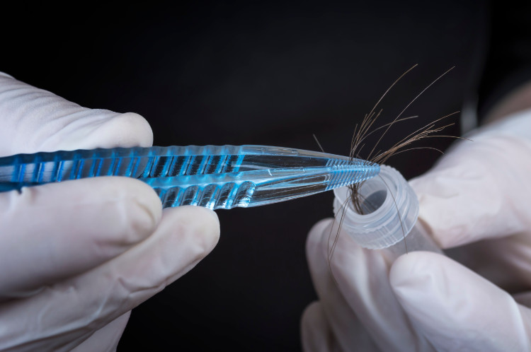 hair caught in tweezers next to the tube