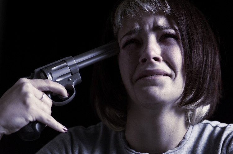 a crying woman holds a gun to her head
