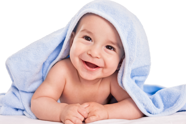 a laughing baby on his tummy, covered with a towel