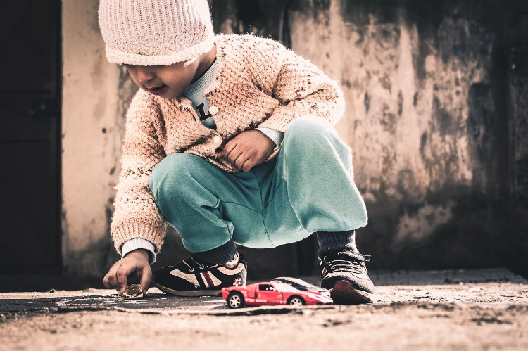 child playing with a stone on the pavement