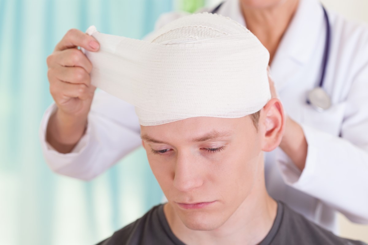 Headache after accident, bandaged head, doctor treats boy with head injury