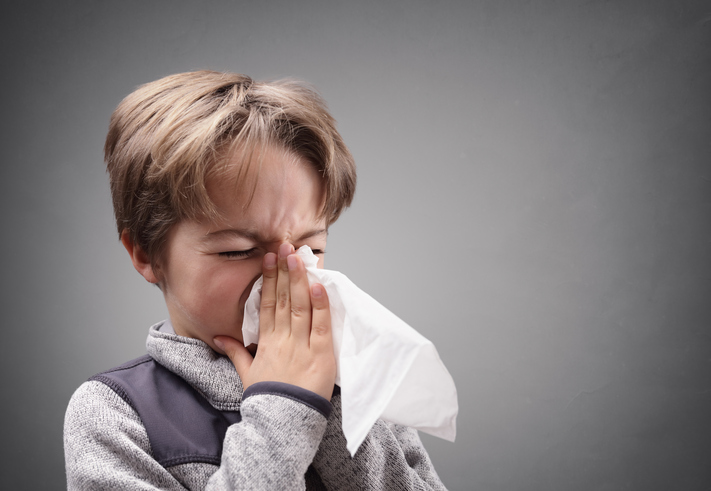 The boy blows his nose, phlegm, into a sanitary handkerchief