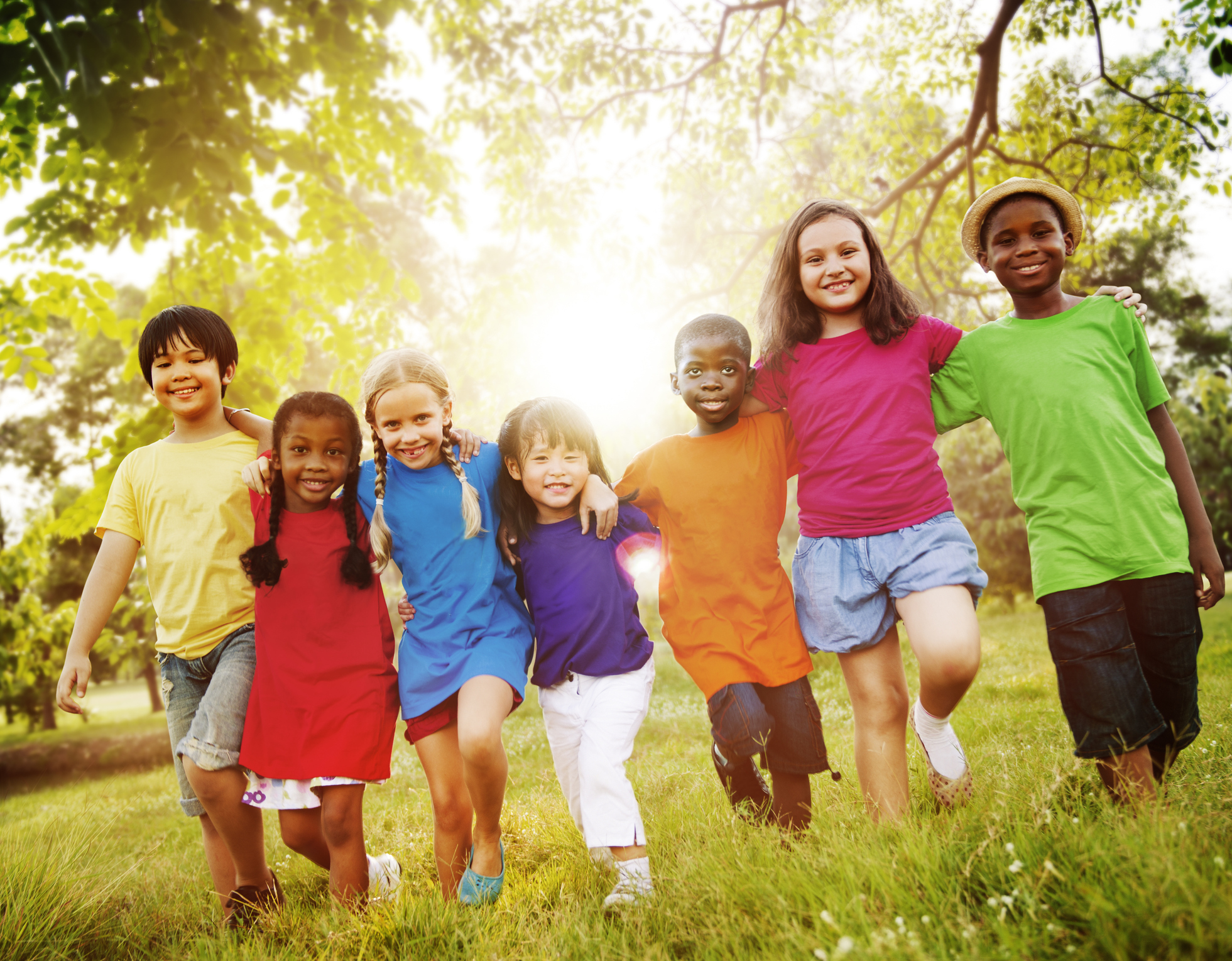 Merry children in nature, 7 children, holding each other by the shoulders, grass, trees