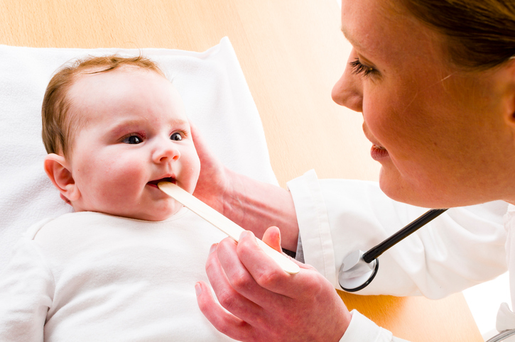 baby with his mouth open, mother looking down his throat with a mallet