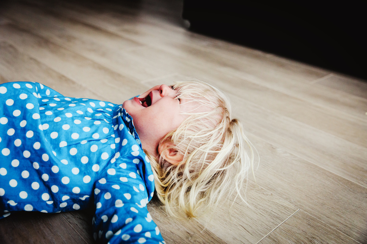 a crying baby throws himself on the ground