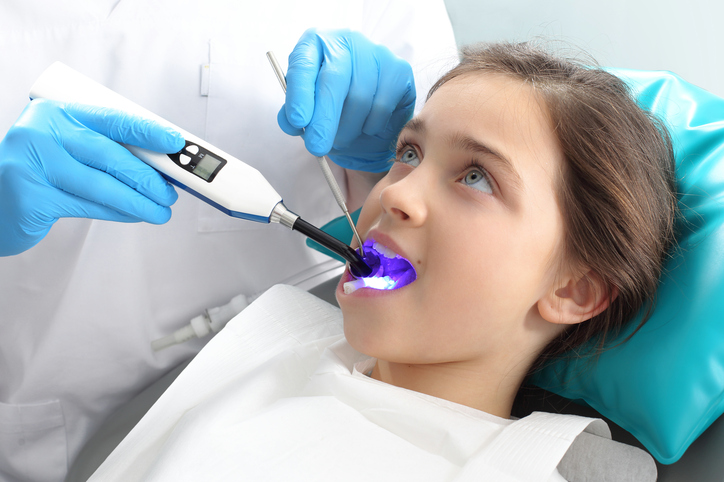 A girl in the dentist's chair being treated by the dentist