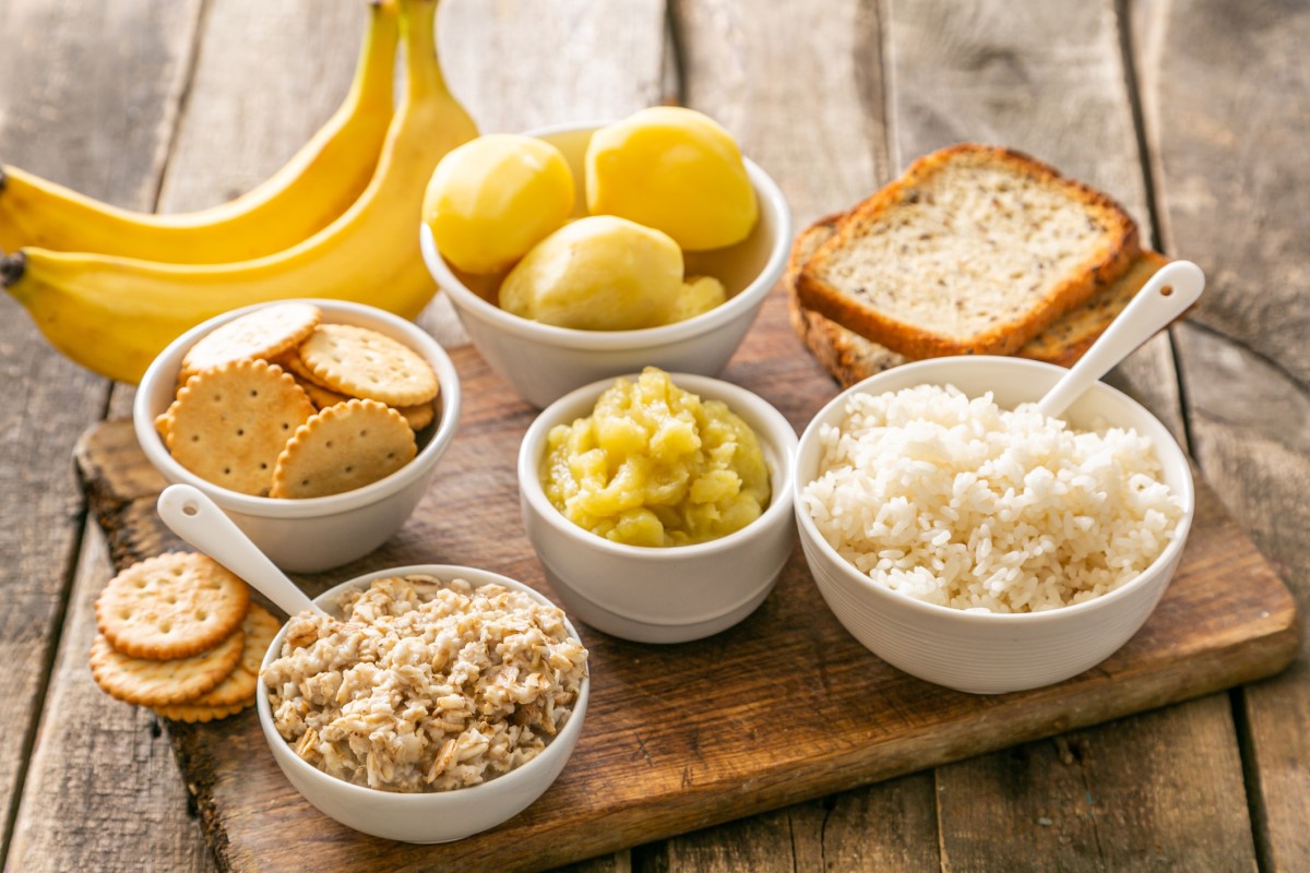 Example of an appropriate diet for acute diarrhea - rice, potatoes, bananas, crackers, crackers, in bowls and on a wooden cutting board.