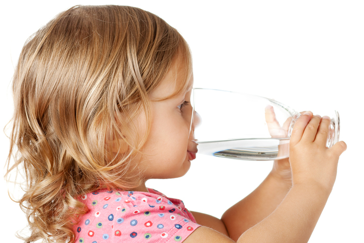 A little girl drinks clean water from a glass