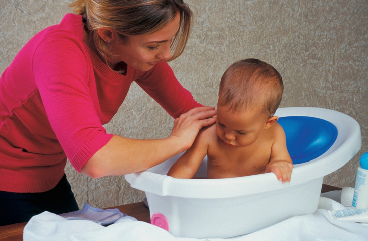 Mother bathing baby in the bathtub