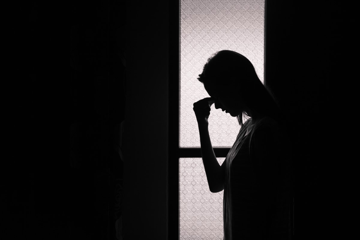 Migraine, sensitivity to light, woman standing in a dark room