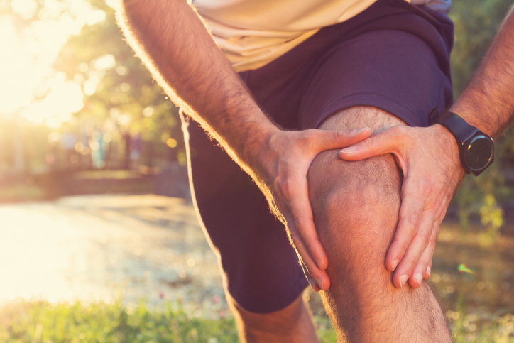 male athlete holding his sore knee