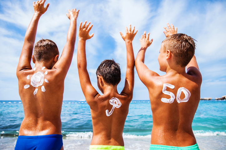 Sunscreen for children with OF 50, children are on the beach by the sea and enjoying themselves, their hands are up