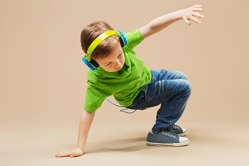 A kid in a green shirt with headphones on does a break dance