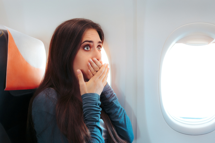 a woman sitting by the window on a plane, she wants to throw up
