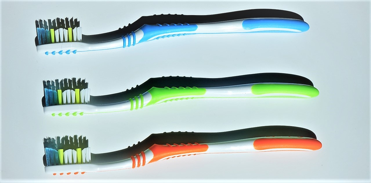 Toothbrushes, colour variants, three pieces, blue on top, green in the middle, orange on the bottom, coloured bristles on the toothbrush head, blue, green and white
