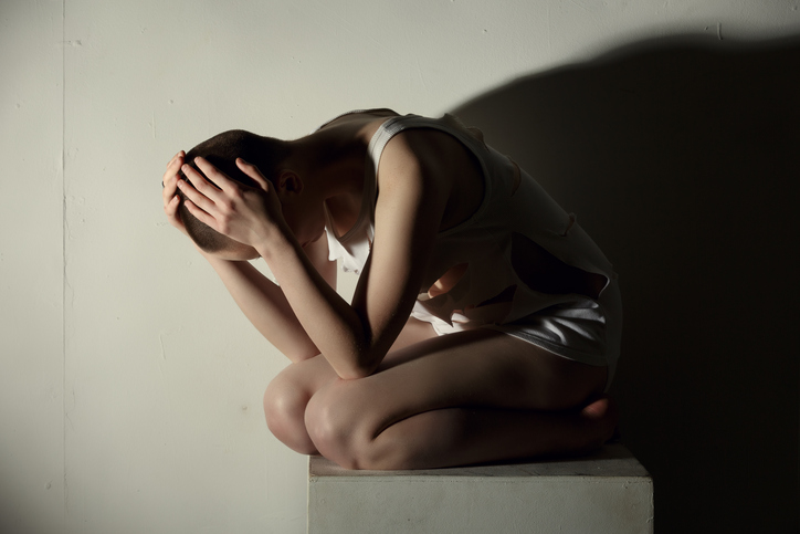 Woman kneeling, depressed, hands on her head