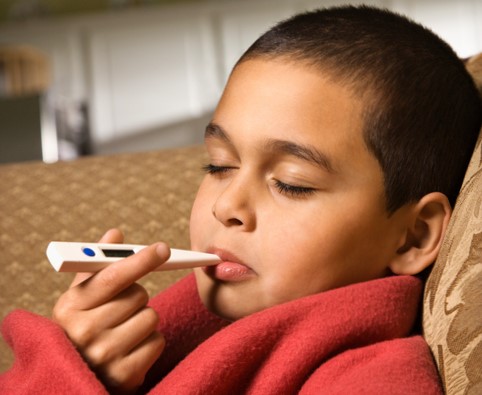 The child measures his body temperature with a digital thermometer in his mouth