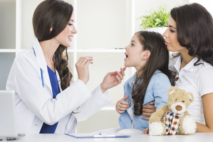 Doctor examines little girl's sore throat