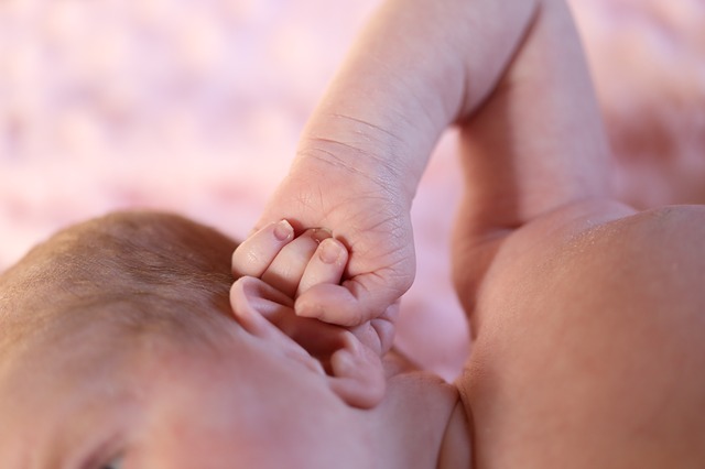 a small child (toddler) holds his ear with his hand