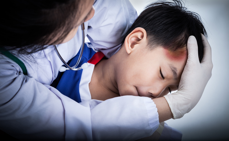 a little boy has a head injury, his forehead is bruised, a doctor is examining him