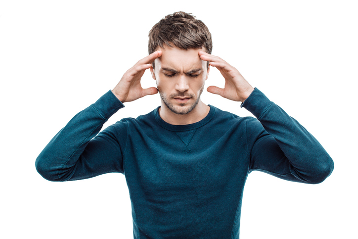 Man has a headache, holds his temples with his hands