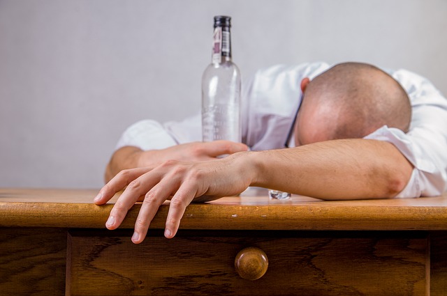 Alcoholism is the cause of mood disorders, a man lies on a table holding an empty bottle of alcohol, an alcoholic