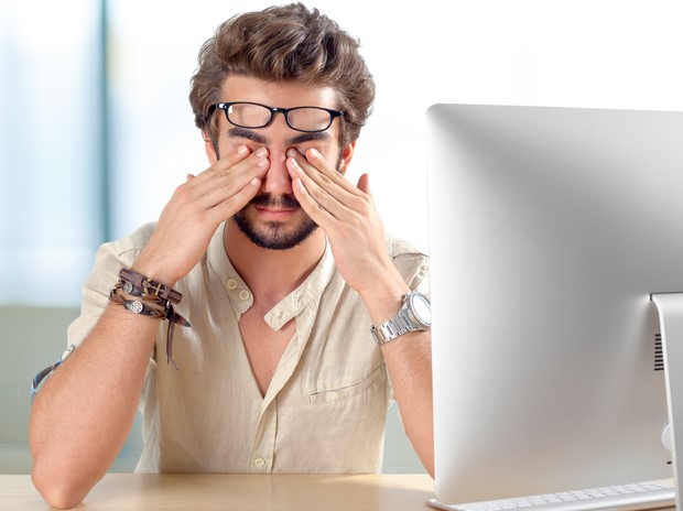 Man keeps his sore eyes, has dry eye syndrome for working at a computer for long periods of time