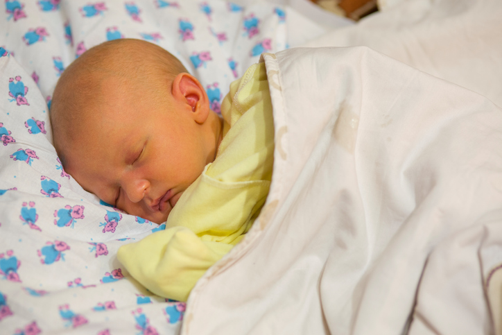 Newborn, lying in cot, dressed, covered, neonatal jaundice, yellowish skin