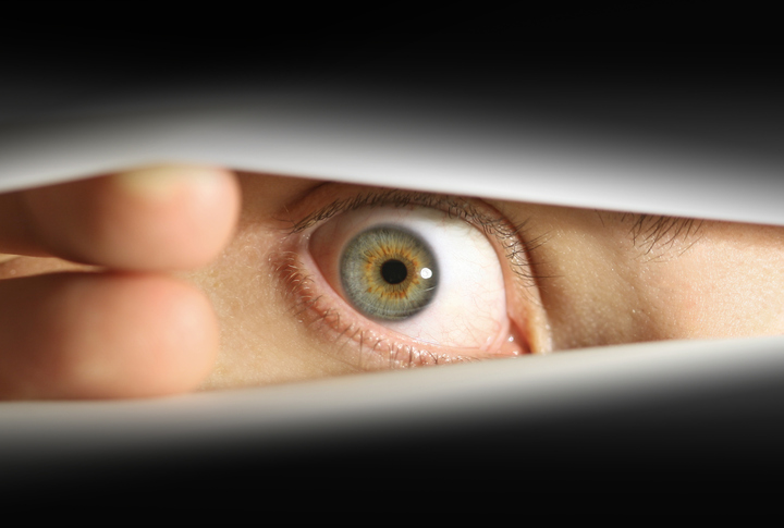 Man hiding behind blinds, looking through a peephole, cutout of face, eye, fingers