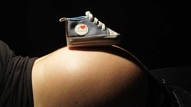 a pregnant woman is lying down with a shoe on her stomach