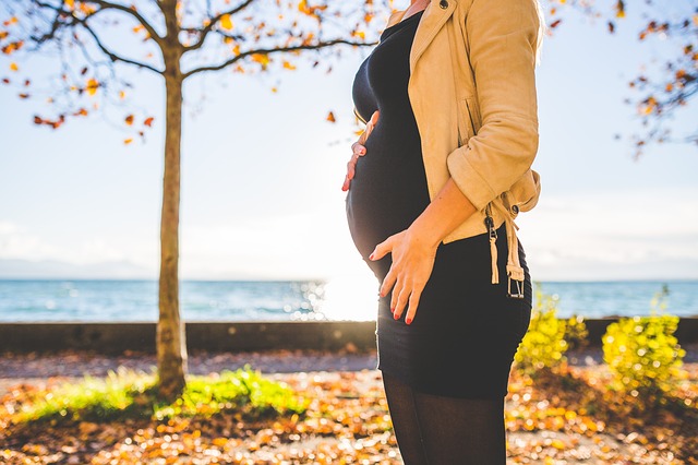 pregnant woman standing in front of tree autumn