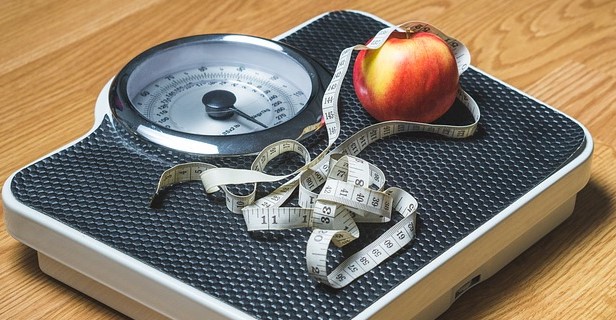 A scale, a tailor's tape measure and an apple