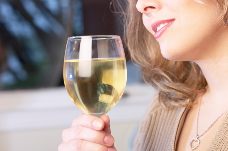 Woman drinking alcohol, wine in a glass, cutout of a woman's face - nose and mouth, holding a glass. Long-term alcoholism as a cause of swallowing disorder