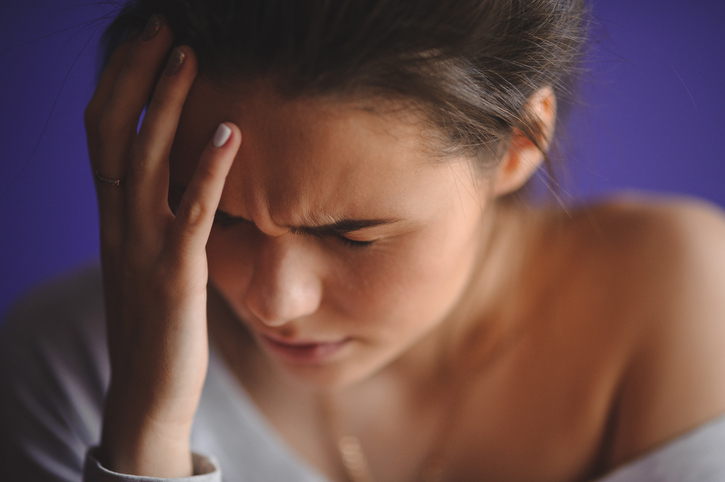 Woman has headache, holding her head with her hands