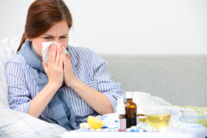 A woman cleans her nose, for a cold, which is the cause of various ailments, in the picture there are medicines, pills, bottle, spray, lemon